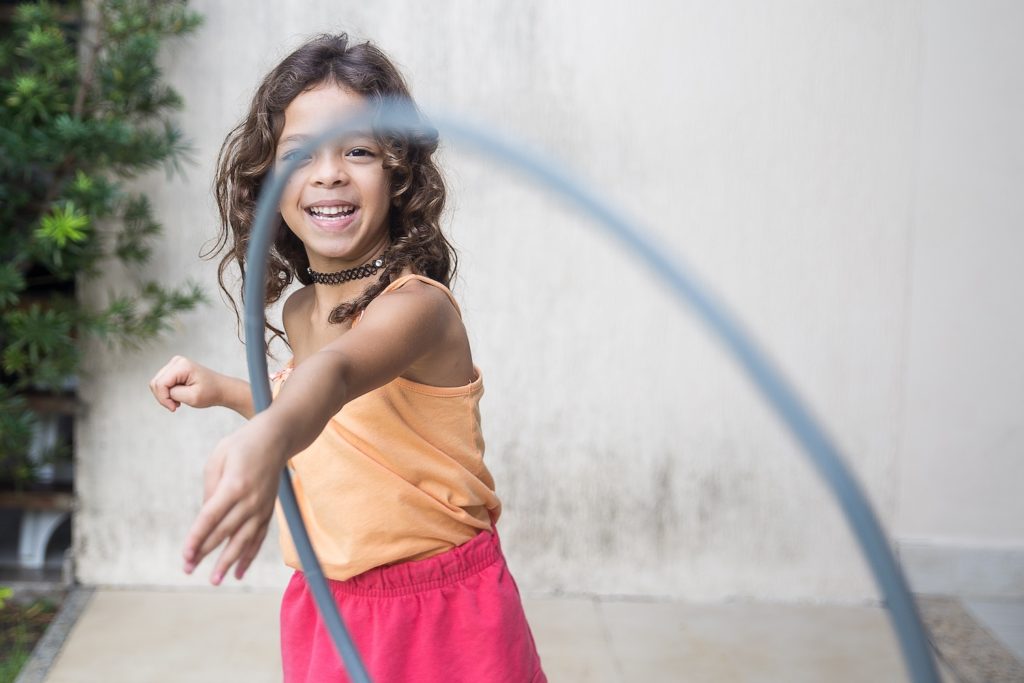 girl throwing hula hoop and smiling